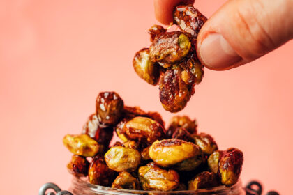 Holding up a cluster of candied pistachios above a jar with more of them