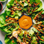 Drizzling a savory sesame sauce onto an eggplant tofu lettuce cup