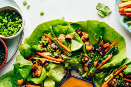 Drizzling a savory sesame sauce onto an eggplant tofu lettuce cup