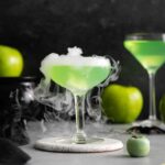 a smoking poison apple martini on a white coaster.