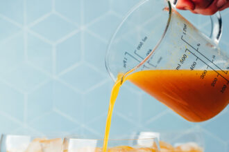 Pouring our spicy passion fruit mocktail recipe from a measuring glass into a serving glass