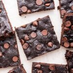 Chocolate chip avocado brownies spread out on a white counter top.