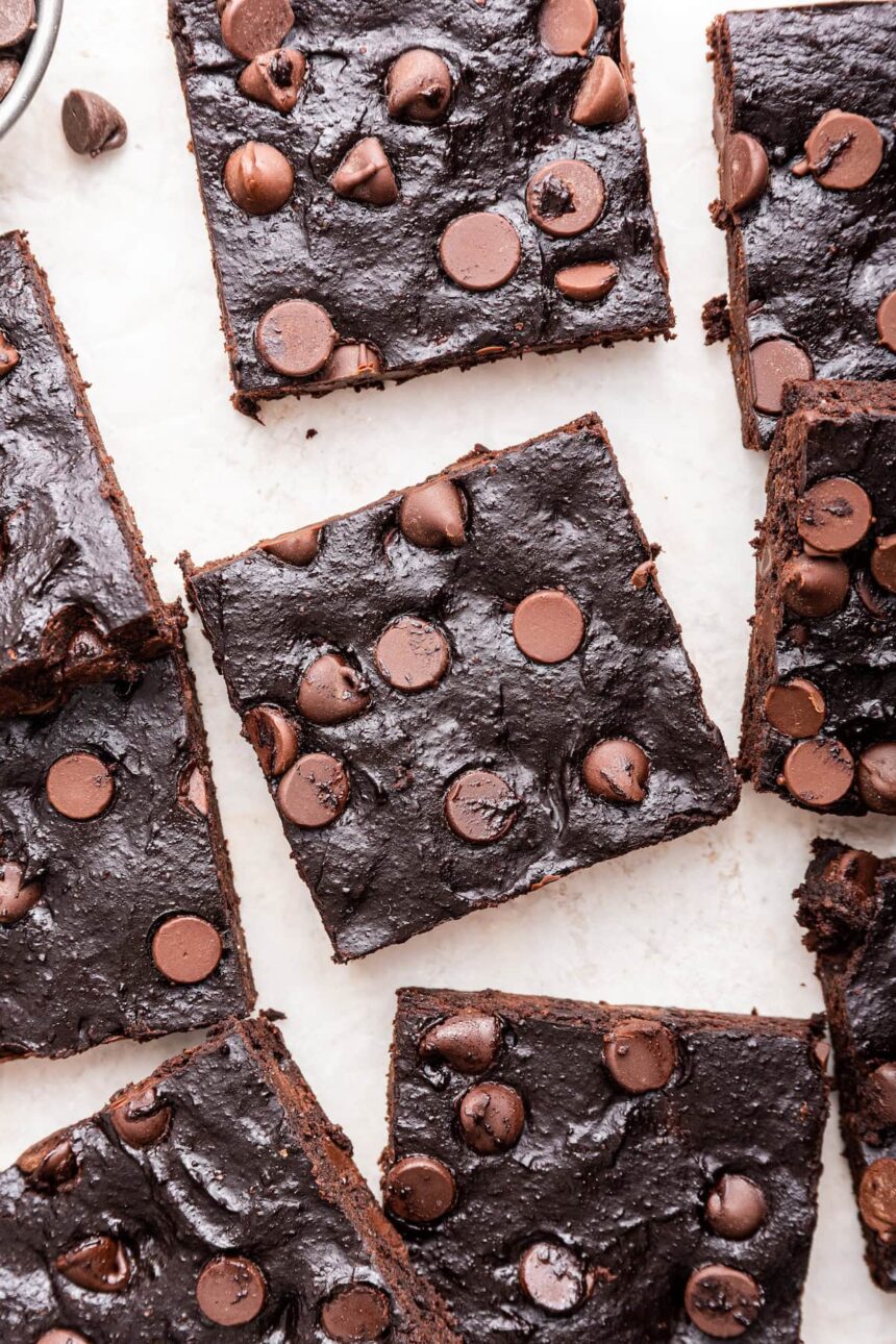 Chocolate chip avocado brownies spread out on a white counter top.