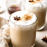 Two mugs of chai latte with cinnamon and star anise.