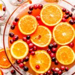 A bowl filled with oranges and cranberries.