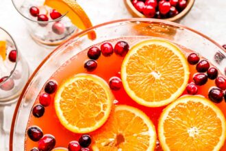 A bowl filled with oranges and cranberries.