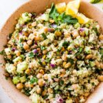 A salad inspired by Jennifer Aniston in a large bowl with quinoa, chickpeas, fresh herbs, and vegetables.