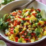 Fruit Salsa in a white bowl with a wooden spoon