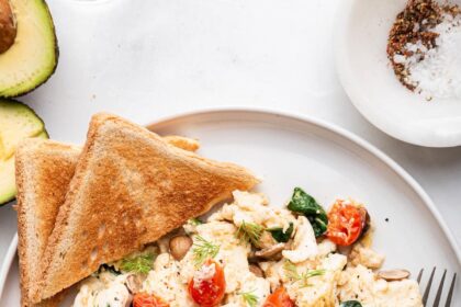 Scrambled egg whites on a plate with two pieces of toast on the side.