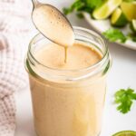 A glass jar filled with the creamy southwest dressing. A silver spoon is in the jar scooping out some of the dressing.