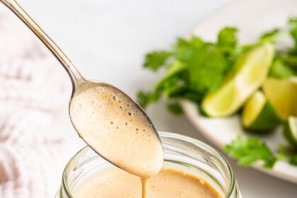 A glass jar filled with the creamy southwest dressing. A silver spoon is in the jar scooping out some of the dressing.