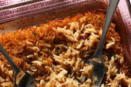 Stick of butter rice baked in a glass baking dish fluffed with 2 forks