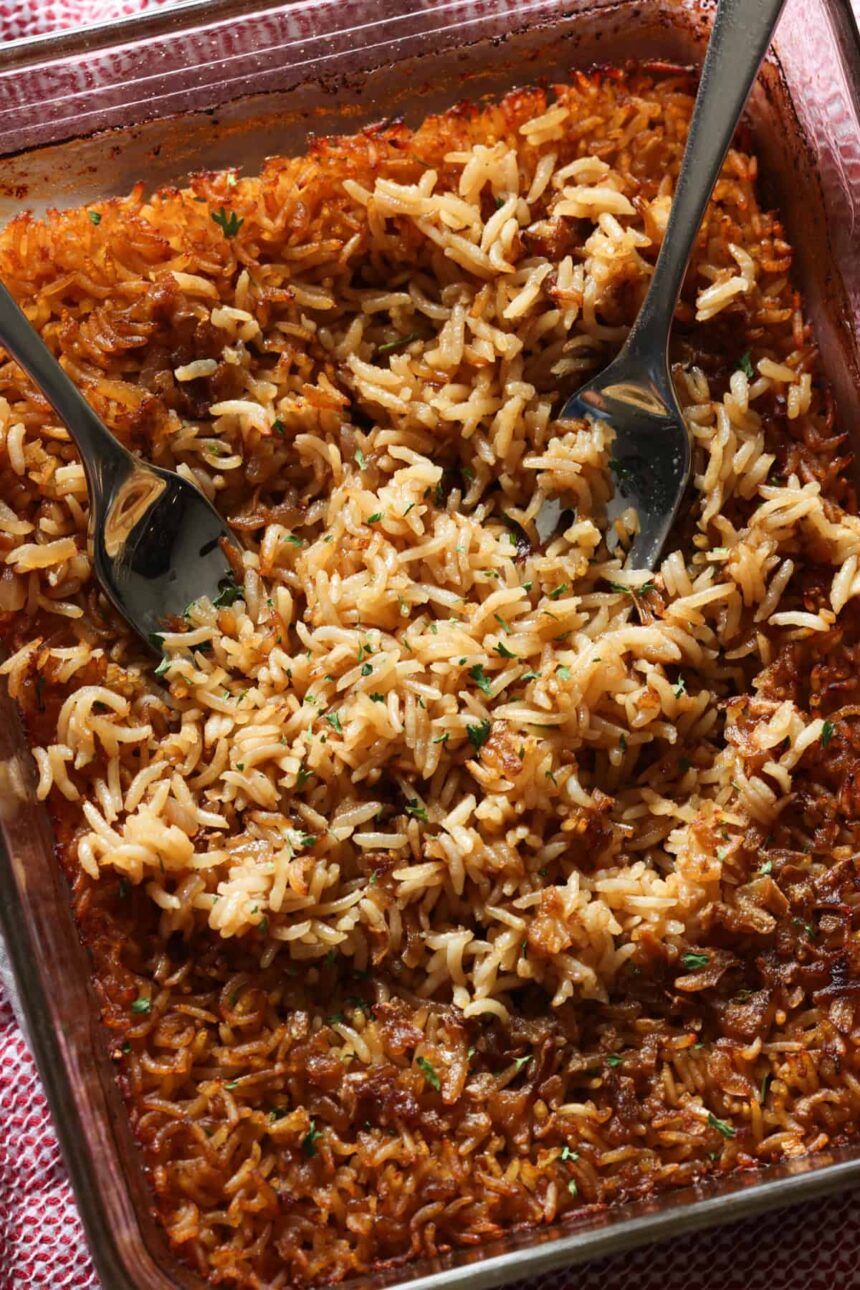 Stick of butter rice baked in a glass baking dish fluffed with 2 forks