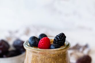 A glass of vanilla overnight oats topped with fresh berries.