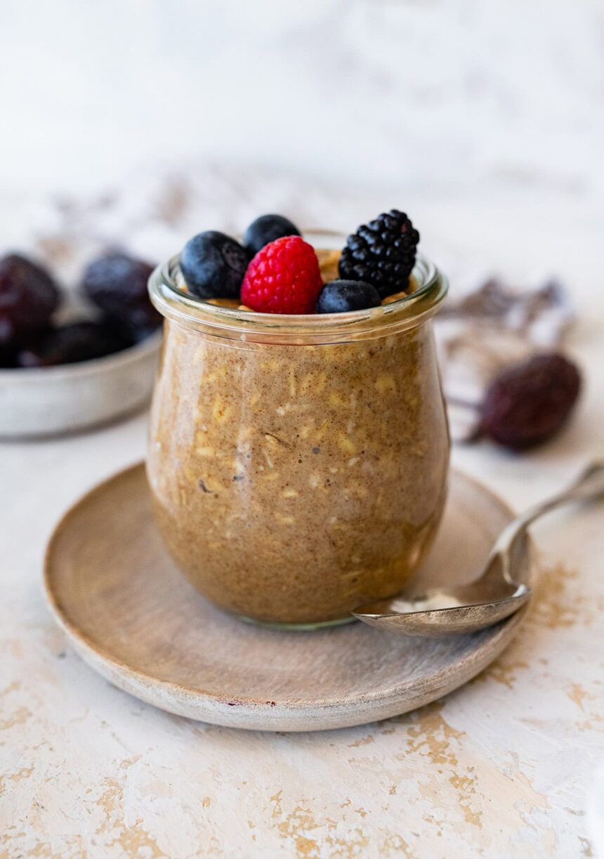 A glass of vanilla overnight oats topped with fresh berries.