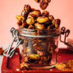 Holding up a cluster of candied pistachios above a jar with more of them