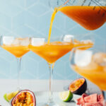 Pouring our spicy passion fruit mocktail recipe from a measuring glass into a serving glass