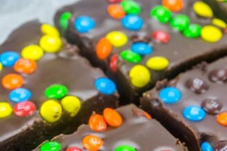 Close up of M&M Fudge Brownies cut into squares on wax paper.