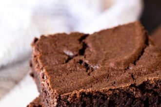 Three squares of the most amazing brownies stacked on top of each other on a white plate