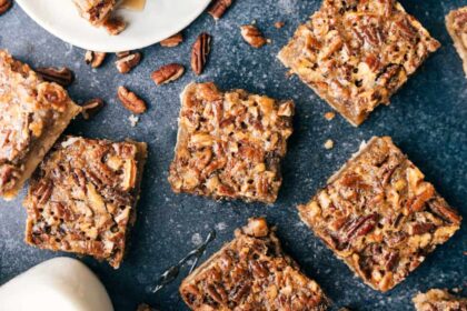 Individual servings of pecan bars scattered out over a black granite counter.