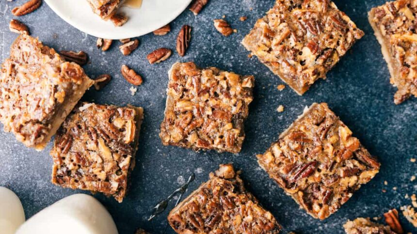 Individual servings of pecan bars scattered out over a black granite counter.