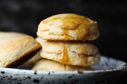 Yeast Biscuits stacked on a plate with honey dripping down the top.