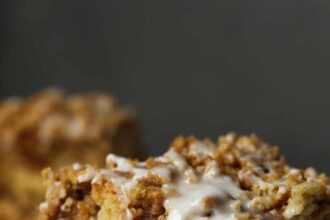 A slice of apple cake on a white plate topped with a thin layer of white glaze icing