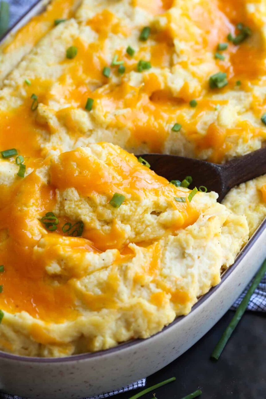 Cheese topped baked mashed potatoes with a wooden spoon to serve