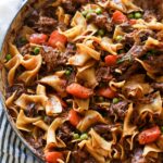 Beef and noodles cooked in a dish with carrots and peas