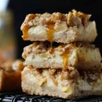 A stack of 3 Caramel Apple Cheesecake Bars on a wire rack