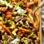 Carne Asada topped french fries with melted cheese and all the nacho toppings.