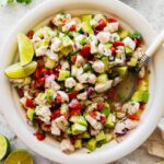 A large white bowl of ceviche with fresh fish, avocado, tomato, cucumber, and avocado.