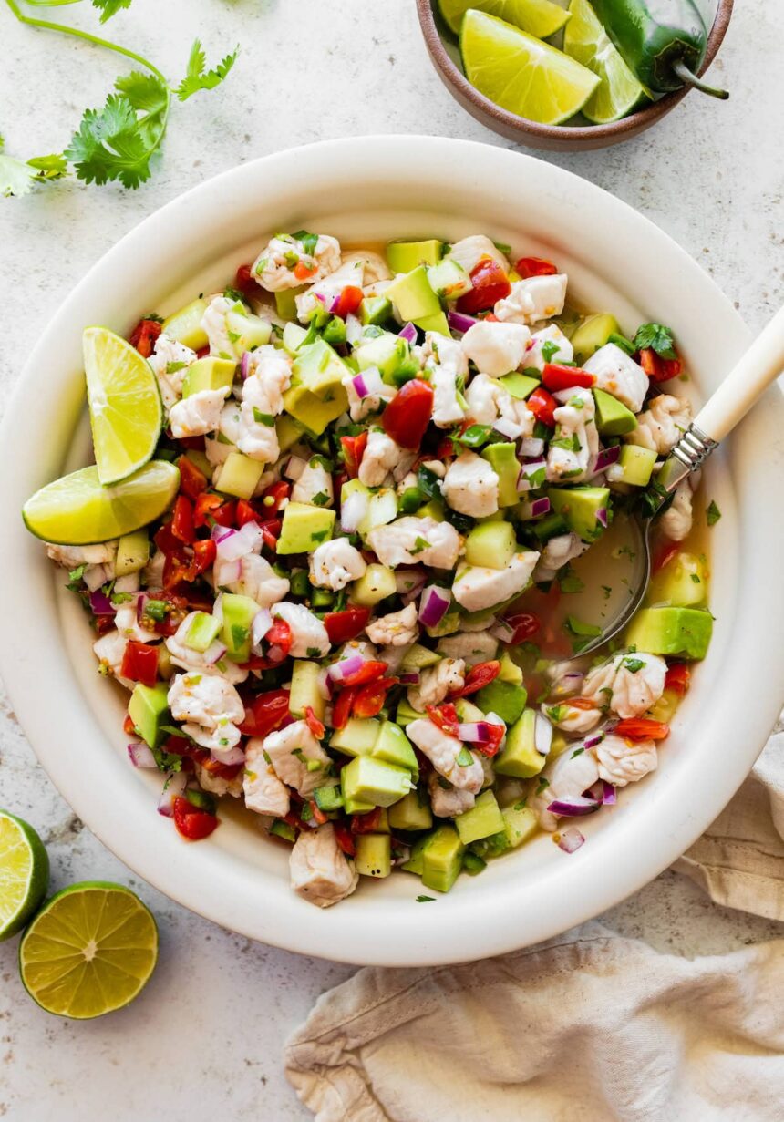 A large white bowl of ceviche with fresh fish, avocado, tomato, cucumber, and avocado.