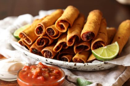 chicken taquitos fried golden brown on a plate with lime wedges