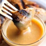 A piece of grilled chicken on a fork coated in homemade chick-fil-a chicken sauce