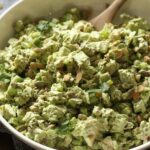 Green goddess chicken salad in a large bowl with a wooden spoon.