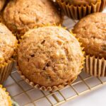 Multiple zucchini muffins on a cooling rack.