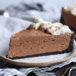 A slice of Nutella cheesecake with Oreo crust and whipped cream.