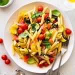 A serving of pasta primavera on a plate topped with fresh herbs.