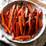 Sliced roasted carrots in a ceramic bowl from above garnished with parsley