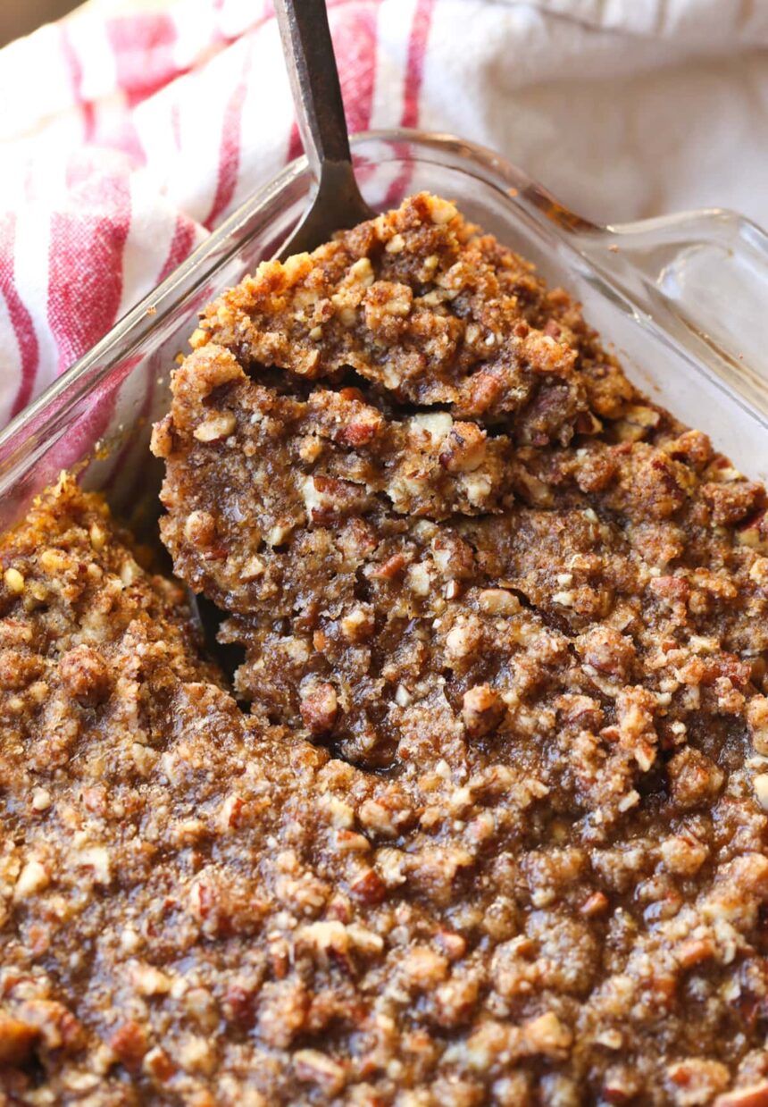 Close up of a serving spoon removing a corner serving from a baking dish full of sweet potato souffle.