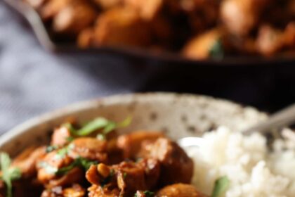 Ginger chicken served in a bowl over rice, garnished with fresh chopped coriander.