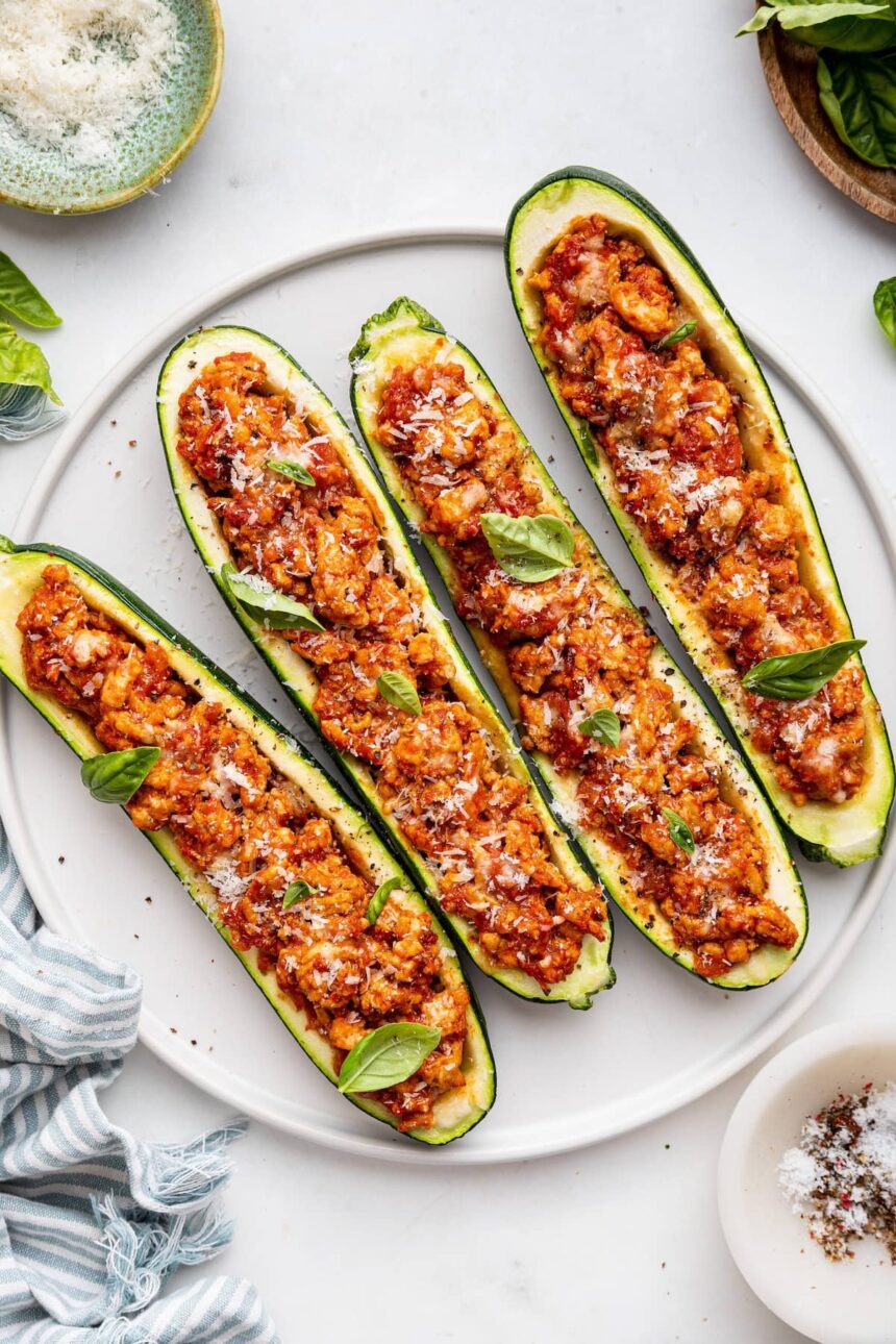 Four turkey zucchin boats topped with fresh herbs and spices.