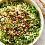 A large bowl of kale crunch salad topped with crushed almonds.