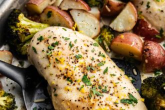 A close up view of sheet pan garlic parmesan chicken and potatoes with broccoli.