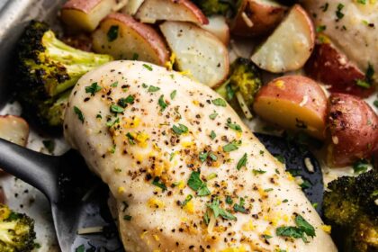 A close up view of sheet pan garlic parmesan chicken and potatoes with broccoli.