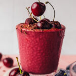 Placing a cherry on top of a glass filled with our chocolate cherry protein shake recipe