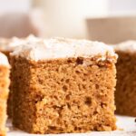 A slice of applesauce cake topped with a cinnamon cream cheese frosting.