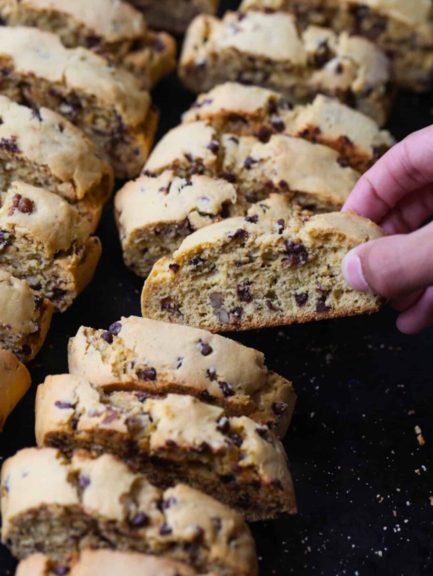 A hand taking a piece of biscotti from a serving tray