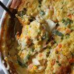 TikTok Chicken Cobbler casserole baked in a round dish with a spoon scooping out a portion